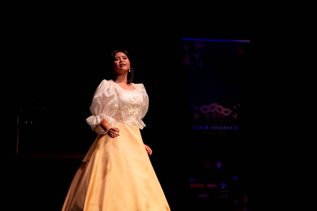 Asiatische junge Frau in langem Ballkleid auf Opernbühne
